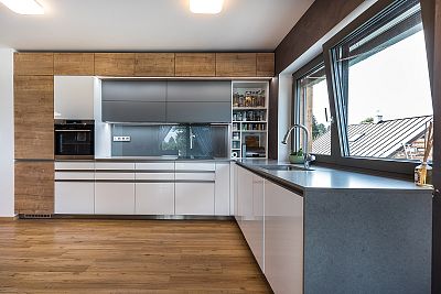 Harmonie bílé lakované povrchové úpravy a dřevěných dekorů v kuchyni na míru od Glanc Kuchyně.
