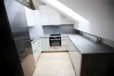 Moderní elegance v podkrovní kuchyni: Bílá lesklá lakovaná kuchyňská linka od Glanc Kuchyně.