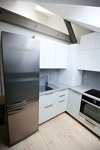 Profesionální vzhled a úložný prostor od Glanc Kuchyně: Volně stojící nerezová lednice v podkrovní kuchyni.
